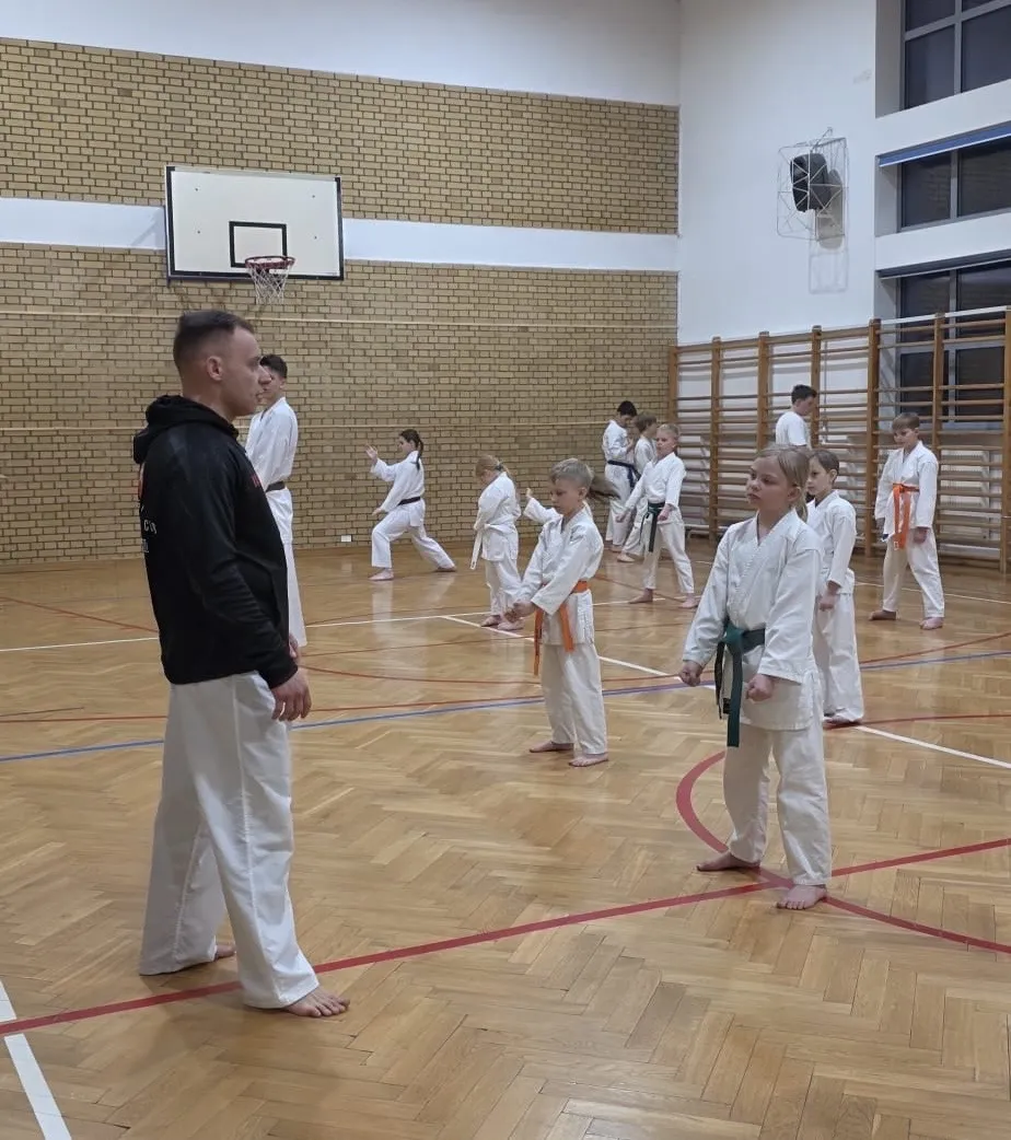 Trener prowadzący trening karate z grupą dzieci w hali sportowej Raion Fight Club