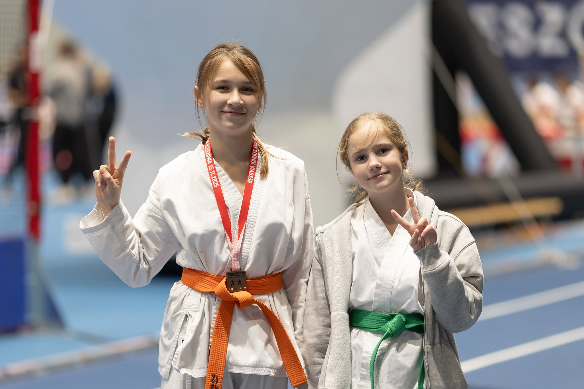 Dwie młode zawodniczki karate w kimonach, jedna z medalem
